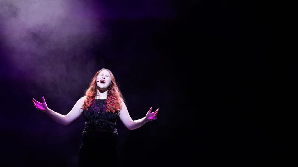 A young woman singing on stage at London Studio Centre