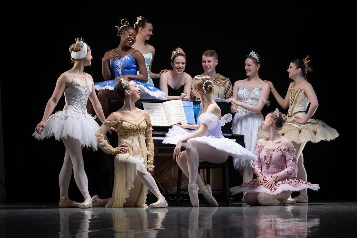 Images Ballet Company pose in ballet outfits around an upright piano